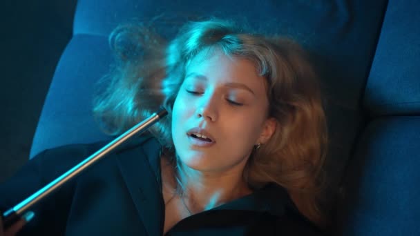 一个长着蓝眼睛的性感女孩躺在夜总会里 抽了很多烟 — 图库视频影像