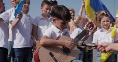 Seyircilerin önünde gitar çalan bir çocuk.