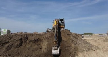 Bir kazıcı, güçlü bir hidrolik ters çevirme kovası olan bir inşaat sahasında bir temel kazıyor..