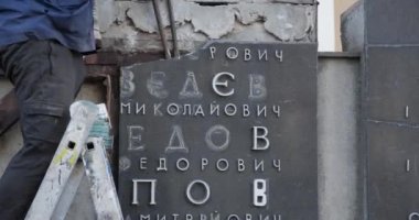 Bir adam anıt plaketi parçalara ayırıyor.