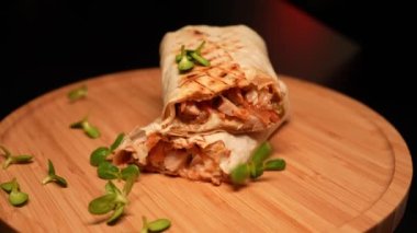 Aşçı, ahşap tahtaya soslu shawarma 'nın yarısını koyuyor. Lezzetli Arap atıştırmalığı servisi