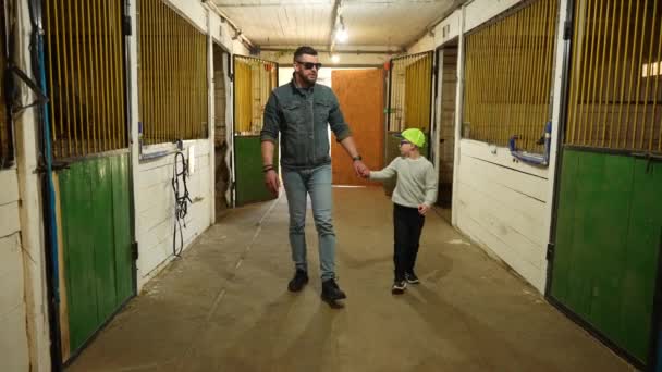 Ein Mann Zeigt Einem Kleinen Jungen Einen Stall Dem Vollblutpferde — Stockvideo