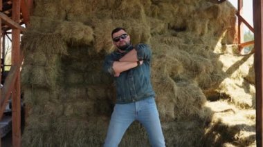 Yetişkin vahşi Amerikalı Teksaslı adam samanlığın yanında kot kıyafetlerle dans ediyor.