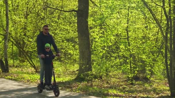 Een Man Een Klein Kind Rijden Een Scooter Het Bos — Stockvideo