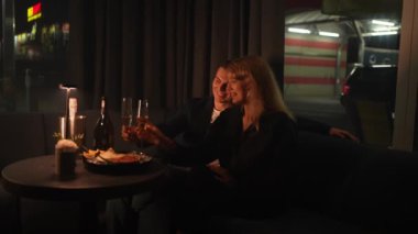 Genç bir çift, bir restoranda bir kadeh şampanyayla şenlik düzenliyor.