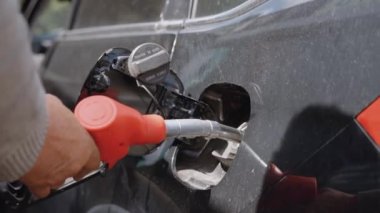 Adamın elindeki gaz tabancası, arabanın benzin deposuna yerleştiriliyor. Araba yakıt ikmali konsepti.