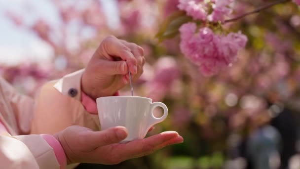Kobieca Ręka Miesza Kawę Tle Kwitnącego Sakura Kwitnie Wiosną — Wideo stockowe