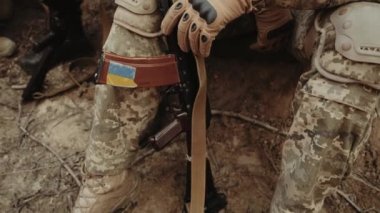 Kalaşnikof saldırı tüfeği tutan Ukraynalı bir askerin erkek ellerine yakın çekim. Ukrayna 'da savaş. Rus saldırıları ve Ukrayna 'nın askeri istilası. Yavaş çekim.