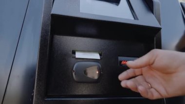 Bir kişi ATM 'den para öder ve çek alır.