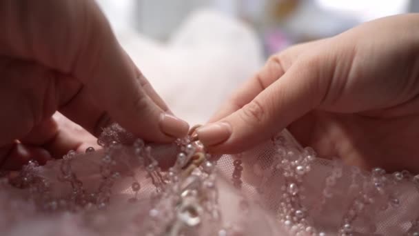 新娘的衣服 一个女人把纽扣系在新娘粉红色节日礼服上 新娘的紧身胸衣制作节日服装 — 图库视频影像