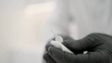 Doktor şırıngadan ilaçla hava salıyor. Bir hemşire şırıngayı aşıyla tutuyor.