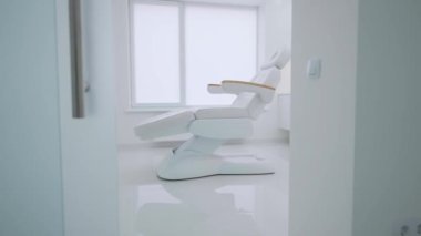 Panoramik pencereleri ve beyaz rahat bir koltuğu olan büyük parlak bir ofis. Suas kozmetik salonu
