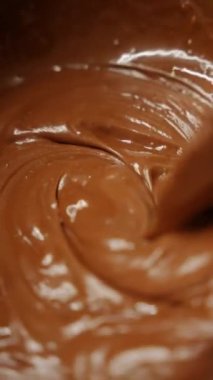 Şef cam kasede kremayı silikon spatulayla karıştırır, tatlı hazırlamak için karıştırır.