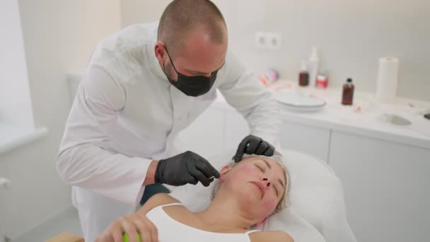 Cosmetólogo Masculino Realiza Procedimientos Lifting Facial Cliente Encuentra Cómodamente Sala — Vídeos de Stock
