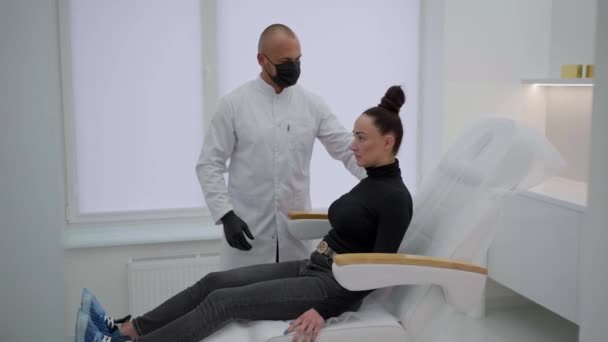 現代のオフィスの医者は診察のために椅子に座っている 女性が椅子に座っている 医療事務所における専門業務 — ストック動画