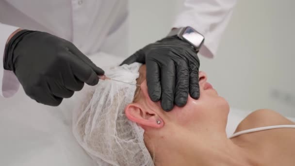 美容師は患者の顔に長い針を挿入します — ストック動画