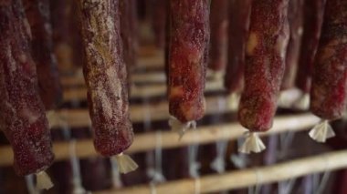 Sosis çubukları kuruyor, et ürünlerini işliyor. Et üretim fabrikasında tütsülenmiş sosisler raflarda olgunlaşıyor. Geleneksel endüstriyel gıda üretim tesisinde sosis olgunlaştırma yöntemi.