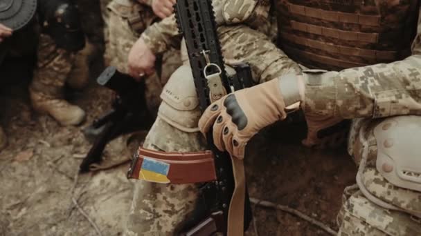 ウクライナ軍の兵士はカラシニコフの攻撃ライフルでトレンチに座っている ウクライナの国旗を持つ武器の閉鎖 ウクライナに対するルシア戦争 — ストック動画
