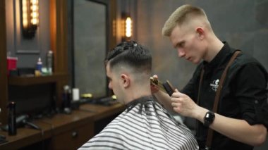 Erkek kafasının, berber dükkanındaki modern elektrikli tıraş makinesi tarafından tıraş edilişinin yakın çekimi. Kuaför malzemeleri ve teknoloji konsepti.