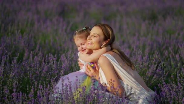 愛する若い母親はラベンダーフィールドを歩いている間に可愛いかわいい赤ちゃんの娘を抱きしめます — ストック動画