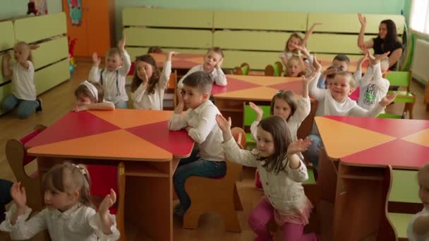 Crianças Pequenas Escola Desenvolvimento Sentam Suas Mesas Levantam Mãos Juntas — Vídeo de Stock