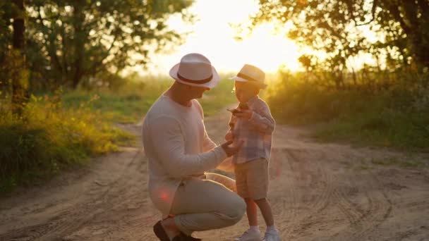 幸せな愛情深い父親と小さなかわいい息子は日没に抱擁しています — ストック動画
