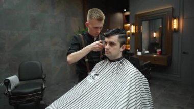 Bir adamın kafasını elektrikli traş makinesiyle tıraş eden bir berberin yakın çekimi. Teknoloji ve kuaförlük kavramı.