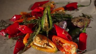 Izgarada ateşte pişmiş sebzeli kırmızı biber. Masanın üstünde ızgara sebze var..