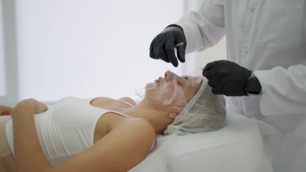 美容师在女人的脸上涂上乳霜 并涂上一层膜 以达到蒸汽浴的效果 — 图库视频影像