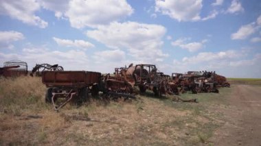 Köy, paslı ve yanmış traktör römork ve hasat makinesini açık havada birleştirin.