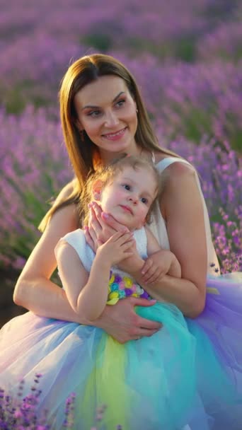 可愛い娘と遊ぶ美しい若い母親のクローズアップ 彼女の腕に赤ちゃんを抱えている母親 ホリデードレスで自然の中で娘と優しい女性を愛する — ストック動画