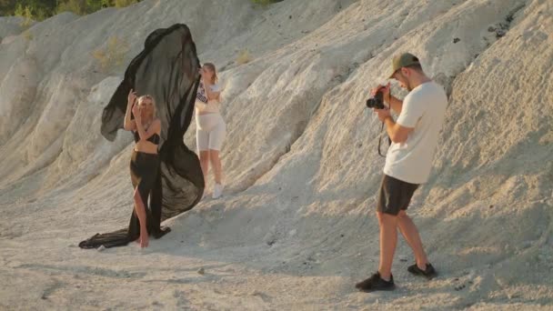 Профессиональная Модель Чёрной Одежде Позирует Фотосессии Стоя Большом Сером Пляже — стоковое видео