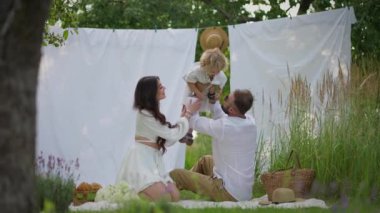 Aile, baba ve anne piknik yaparken küçük oğullarıyla oynuyorlar.