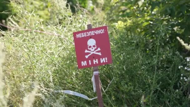 红色危险地雷警告标志和栅栏带在田野中央 俄乌战争 俄罗斯军队在乌克兰境内埋设了地雷 地雷和手榴弹 — 图库视频影像