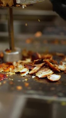 Bir adam fast food restoranında keskin bir bıçakla ince dilimler halinde jiroskop eti keser.