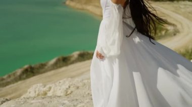 Mavi okyanusun kıyısındaki dağın tepesinde beyaz elbiseli güzel bir gelin.