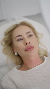 Bir kadın güzellik salonunda dudak büyütme ve yüz gerdirme ameliyatından sonra aynaya bakar.