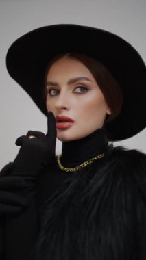 Kapalı alanda gri arka planda kameraya bakan genç, lüks ve seksi bir kadının yakın plan portresi. Makyajlı, kahverengi gözlü profesyonel bir modelin yüzü..