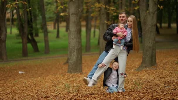 一家人带着小孩在秋天的公园里散步 在大自然中共度时光 爸爸和孩子们都在拥抱和笑 — 图库视频影像
