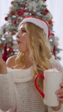 Noel Baba şapkalı güzel bir kız evde müzik dinleyerek, tatlı kekler yiyerek ve dinlenerek vakit geçiriyor..