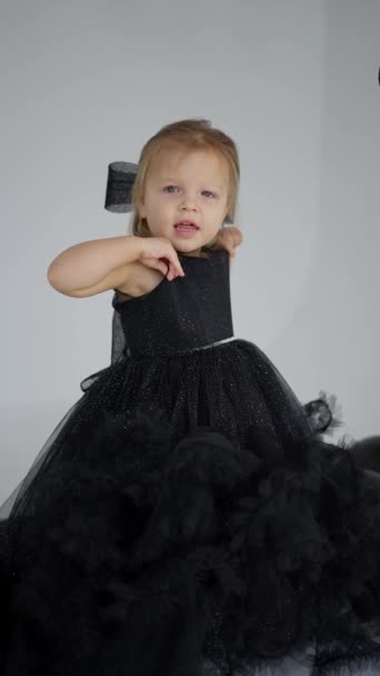 お祝いの黒いドレスで笑っているかわいい金髪の少女 — ストック動画