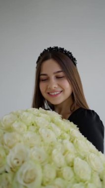 Çiçeklerin kokusunu soluyan esmer bir kadının portresi. Elinde bir buket çiçekle gülümseyen genç bir kadın.