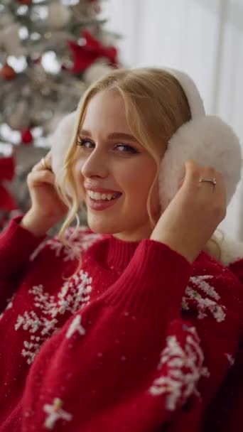 カメラを見て明るいクリスマスガーランドの近くで微笑んでいる若い幸せな少女の肖像画 — ストック動画