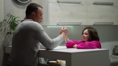 Bir baba bir çocukla oynar. Kız ve baba mutfakta aem güreşinde yarışıyorlar..