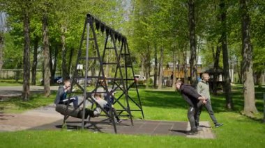 Mutlu çocuklar salıncakta sallanıyor ve güzel bir yaz gününün tadını çıkarıyor. Neşeli ve mutlu çocukluk kavramı