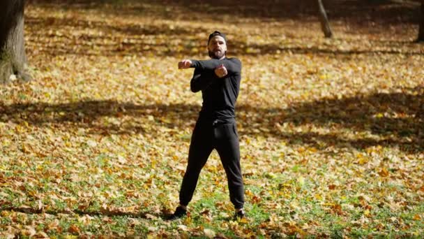 黄色い葉で覆われた秋の公園でフィットネスをする運動的な白人青年 — ストック動画