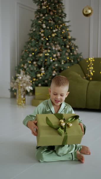 Mutlu Bir Çocuk Süslü Bir Noel Ağacının Yanında Oturuyor Elinde — Stok video