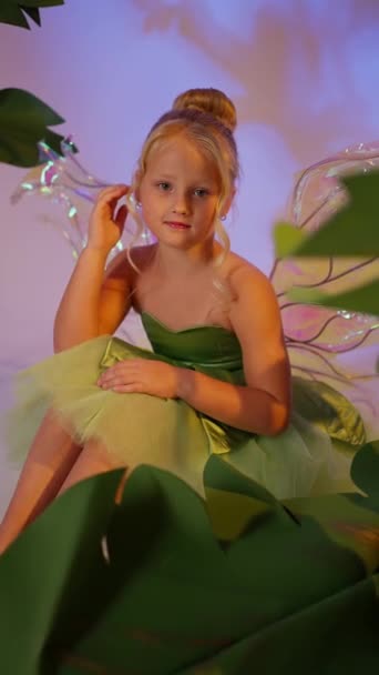 おとぎ話の花の背景に緑のドレスで翼を持つ幸せな美しいファンタジーの子供天使 — ストック動画