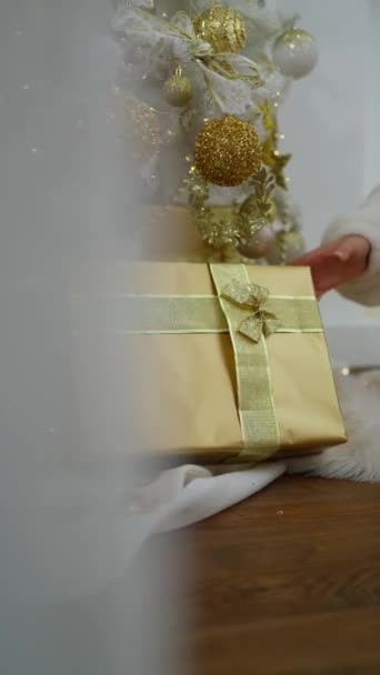 Een Vrouw Ontvangt Een Kerstcadeau Thuis Bij Een Versierde Kerstboom — Stockvideo