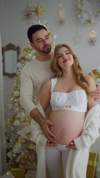 Zwanger Paar Knuffelen Thuis Nieuwjaarsvakantie Buurt Van Kerstboom — Stockvideo